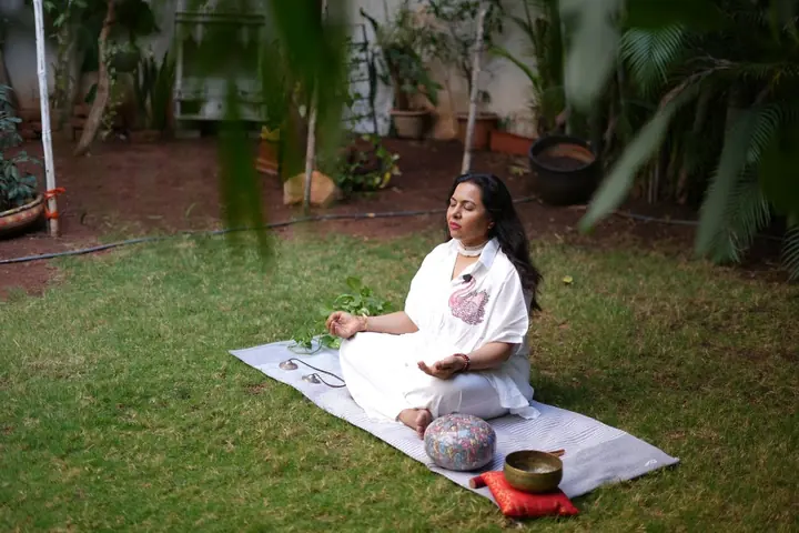 Neelam meditating in her garden with singing bowls