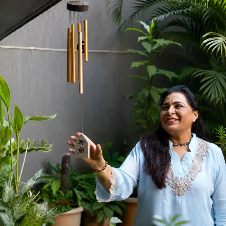 Neelam Chawlla smiling under wind chimes in her garden